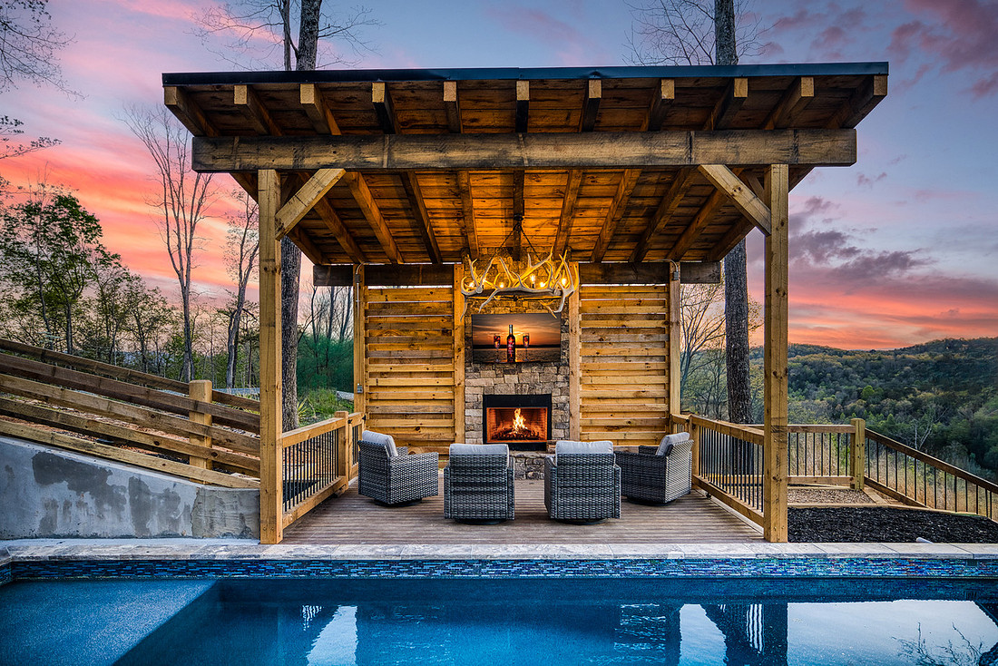 Covered outdoor fireplace and seating beside a pool at dusk, Airbnb amenity photography in Blue Ridge GA