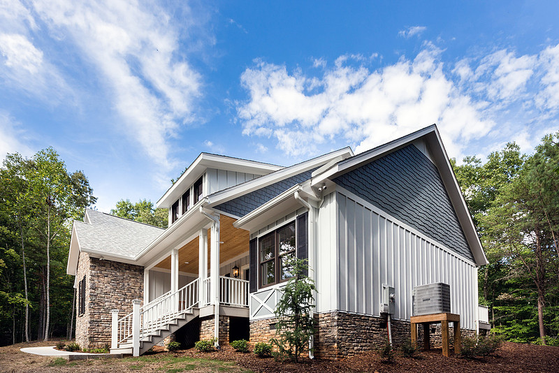 Front and side exterior of a white farmhouse with a wraparound porch, real estate photography in North Georgia