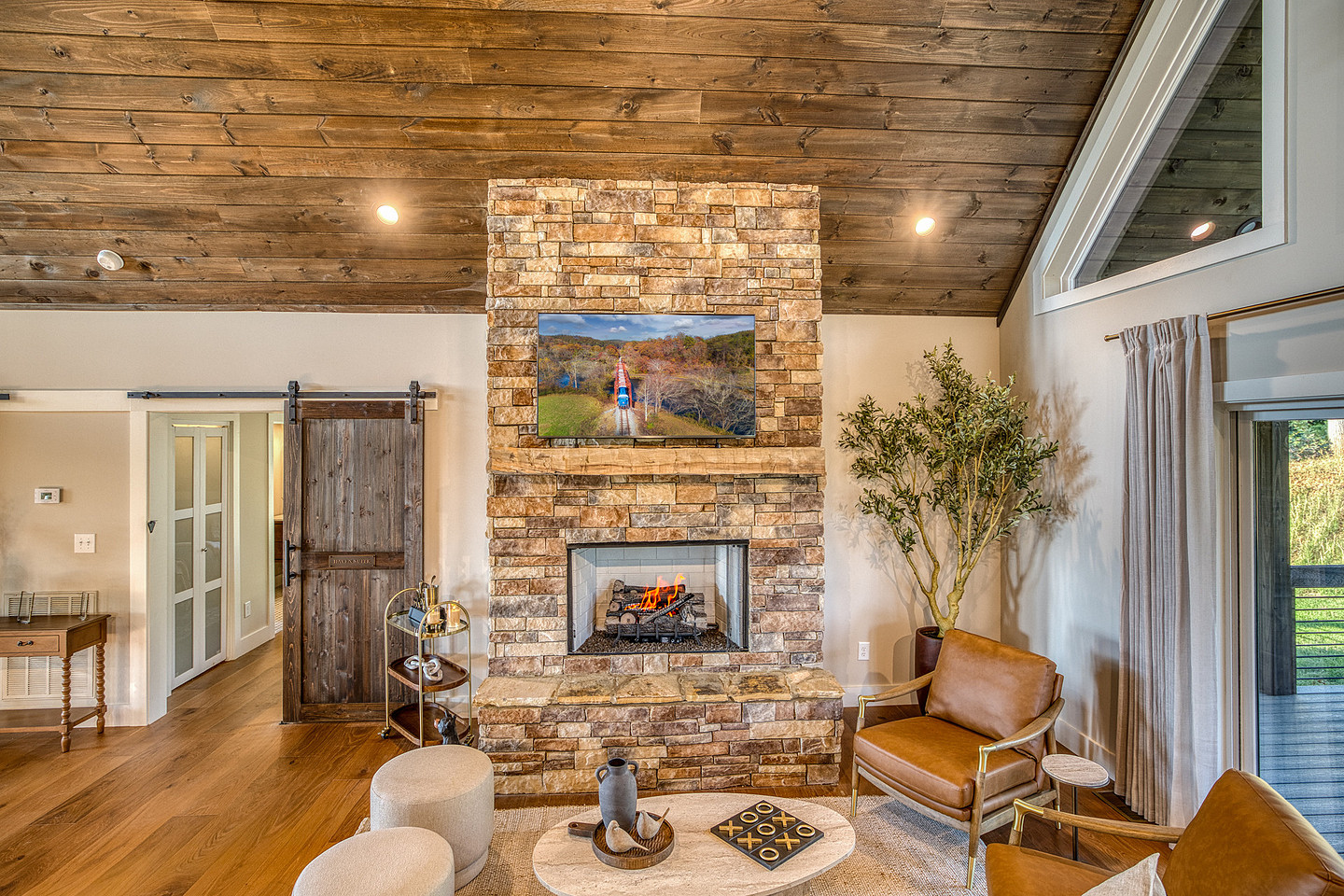 Living room with stone fireplace and vaulted wood ceiling